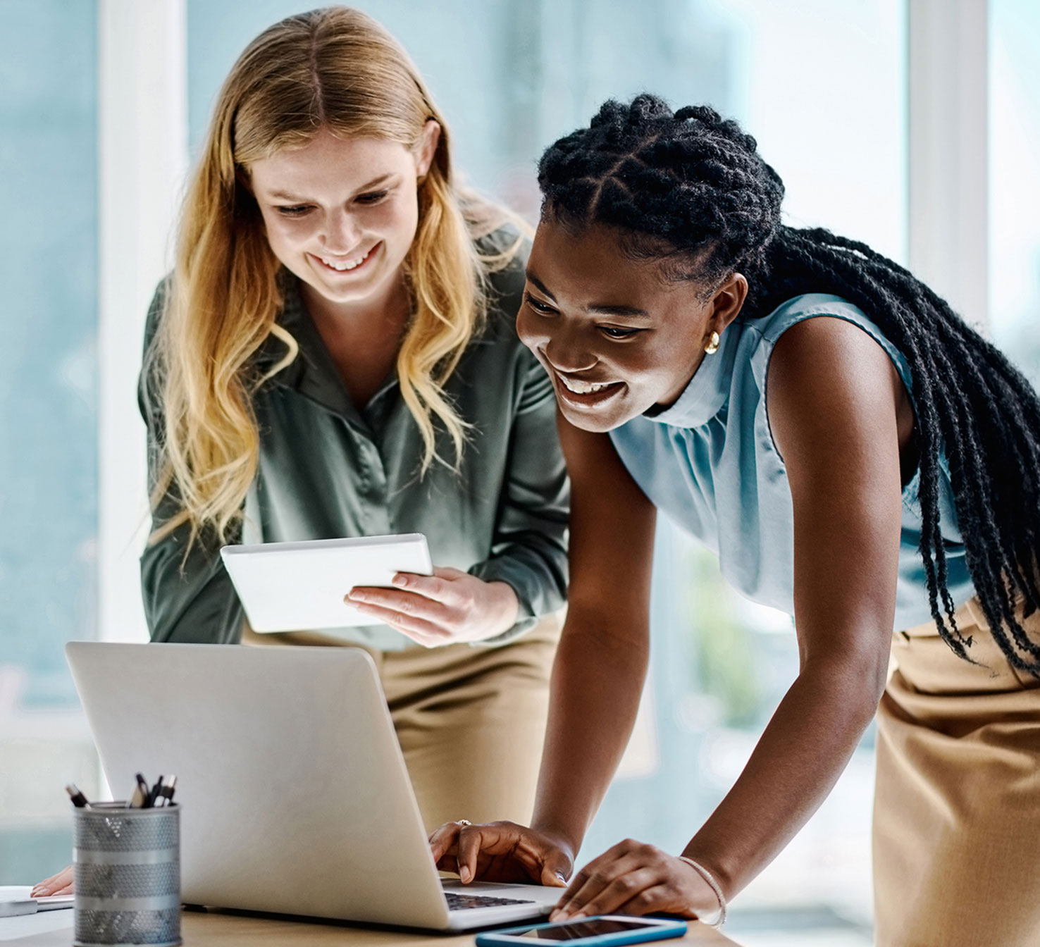 Female students smiling while looking at laptop screen together